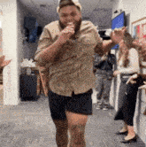 a man wearing shorts and a hat is singing into a microphone