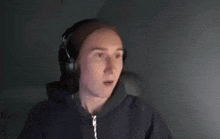 a young woman wearing headphones and a hoodie looks at the camera