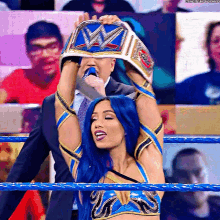 a woman in a wrestling ring is holding a wwe championship belt over her head