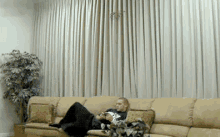 a man is sitting on a couch in a living room reading a book
