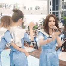 a woman in a blue dress is singing into a microphone while standing next to another woman .
