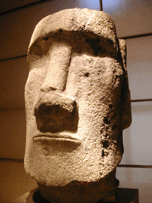 a statue of a man 's face is sitting on a pedestal in front of a wall