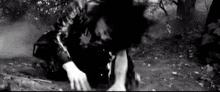 a black and white photo of a man kneeling down in the dirt .