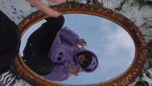 a person in a purple hoodie is standing in front of a mirror .