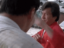 a man in a red jacket is giving another man a fist bump