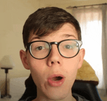 a young man wearing glasses looks surprised with his mouth open