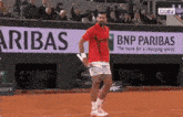 a man playing tennis in front of a bnp paribas banner