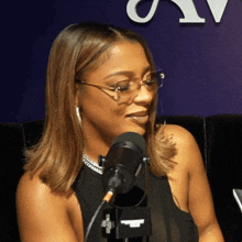 a woman wearing glasses is sitting in front of a microphone that says " recording studio "