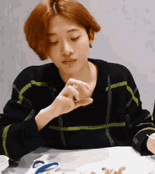a woman is sitting at a table with a plate of food and scissors