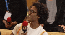 a man wearing glasses is holding a red microphone with a logo that says ' geek ' on it