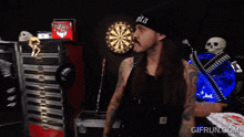a man standing in front of a dart board wearing a beanie that says nita on it