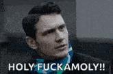 a man wearing a scarf around his neck is making a funny face and saying holy fuckamoly .
