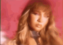 a blurry picture of a woman 's face with long hair against a pink background .