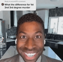 a man in a suit and tie is smiling in a kitchen while wearing ear buds .