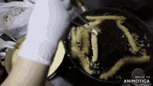 a person is frying french fries in a frying pan with the words made in animotica on the bottom