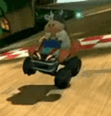a stuffed animal is driving a toy car on a track .