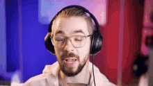a man with glasses and headphones is singing into a microphone with his eyes closed