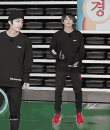 a man in a fila sweatshirt stands next to another man