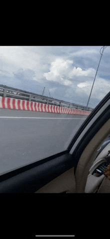 a car driving down a highway with a red and white barrier