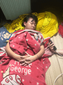 a woman is sleeping under a pink blanket that says george