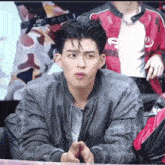 a young man in a gray jacket is making a funny face while sitting at a table .