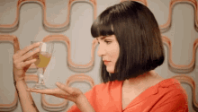 a woman in a red shirt is holding a glass with a green liquid in it