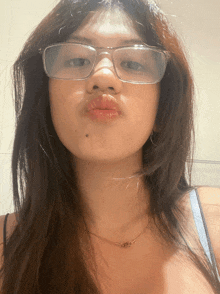 a woman wearing glasses and a necklace makes a silly face
