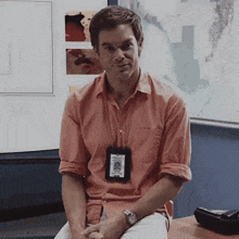 a man wearing an orange shirt has a badge around his neck that says ' dexter ' on it