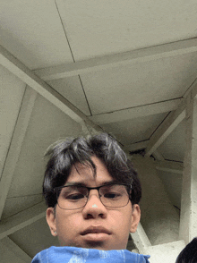 a man wearing glasses and a blue scarf looks at the camera