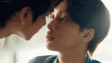 a couple of young men are kissing each other on the forehead .