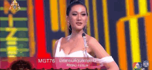 a woman in a white dress is standing in front of a microphone on a stage in front of a colorful background .