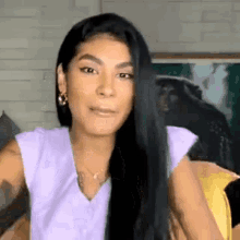 a woman with long black hair is wearing a purple shirt .