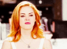a woman with red hair wearing a white tank top and a necklace