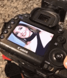 a person is holding a canon camera with a picture of a woman on the screen
