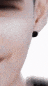 a close up of a person 's face with a pair of black earrings on .