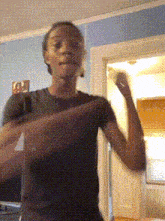 a man in a black shirt is dancing in a room with a picture of a woman on the wall behind him