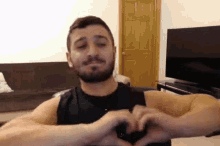 a man with a beard is making a heart with his hands .