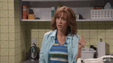 a woman in a blue shirt is standing in a laundry room with cnn written on the wall behind her