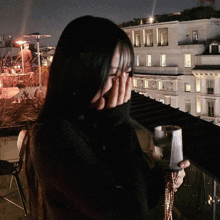 a woman covering her face while holding a glass