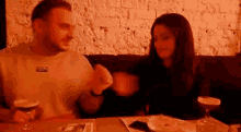 a man and a woman are sitting at a table in a restaurant with drinks .