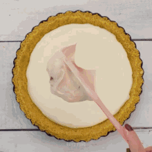 someone is spreading whipped cream on top of a pie crust