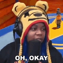 a woman wearing a teddy bear hat and headphones says oh okay
