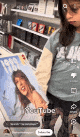a girl in a blue shirt is holding a record that says 1989 on it