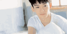 a young man in a white shirt is sitting on a bed .