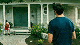 a man in a blue shirt stands in front of a house with the number 9117 on the front door