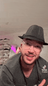 a man wearing a hat and glasses is smiling and looking at the camera .