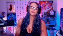 a woman wearing glasses and headphones is standing in front of a microphone in a room .