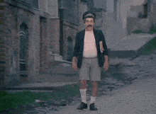 a man with a mustache wearing shorts and socks walks down a street