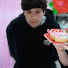 a man in a black hoodie looks at a plate of cupcakes