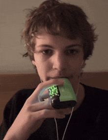 a young man is holding a green device that says ' xbox 360 ' on it